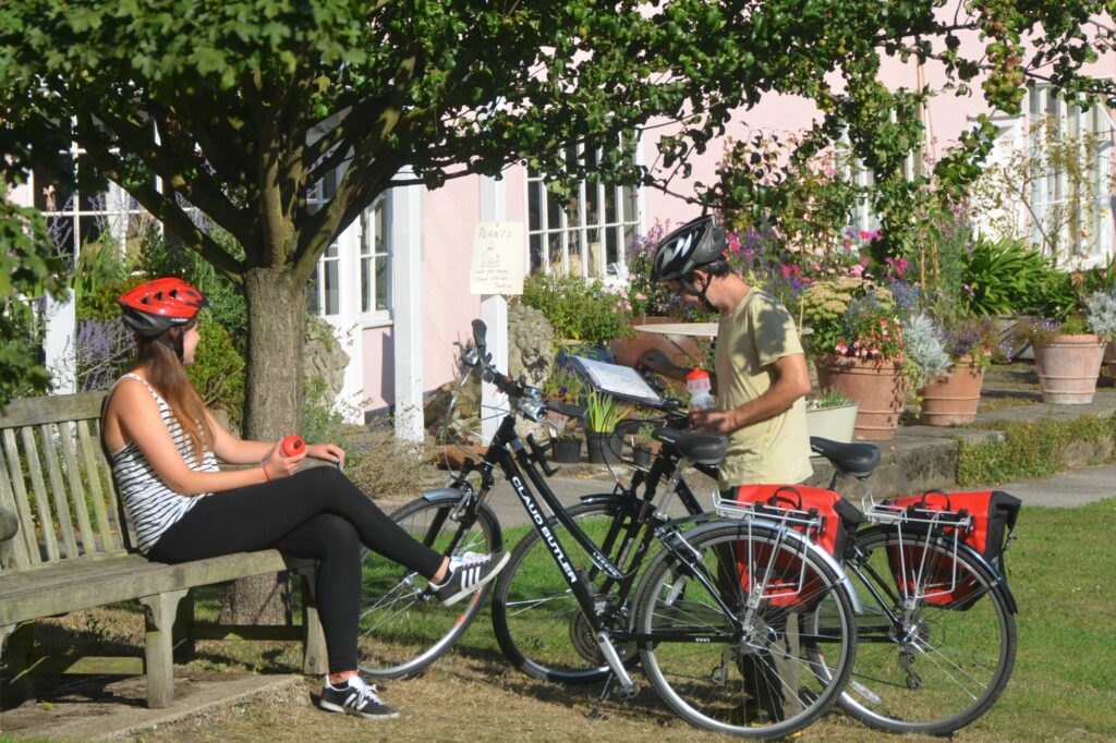 Cyclists stop at a Suffolk village green to look at maps and rest ready for the next part of their cycling adventure